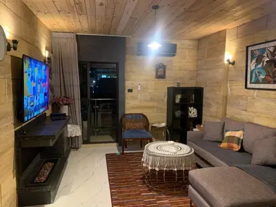 a living room with a couch and a flat screen tv at Aqaren Apartment in Amman