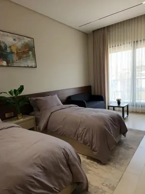 a bedroom with two beds and a chair and a window at كمباوند المطار شقه مفروشة in Amman