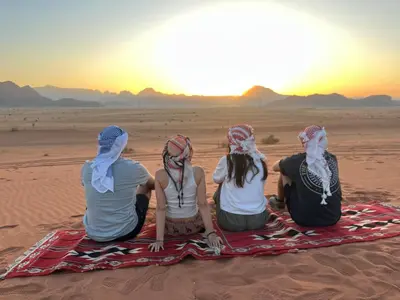 four girls sitting in the desert watching the sunset at Wadi Rum Star Haven camp in Wadi Rum