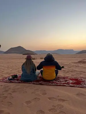 two people sitting in the desert watching the sunset at Wadi Rum Star Haven camp in Wadi Rum