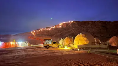 a truck parked in front of a mountain at night at SARH lUXURY CAMP in Wadi Rum