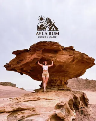 a woman standing on a rock in the desert at ALYA RUM LUXURY Camp in Wadi Rum
