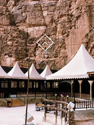 a building with white tents in front of a mountain at ALYA RUM LUXURY Camp in Wadi Rum