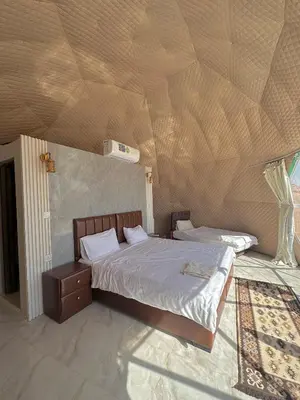 two beds in a bedroom with a wooden ceiling at ROYAL LANCASTER lUXURY CAMP in Wadi Rum
