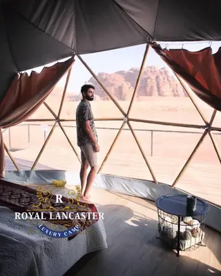 a man standing inside a yurt in the desert at ROYAL LANCASTER lUXURY CAMP in Wadi Rum