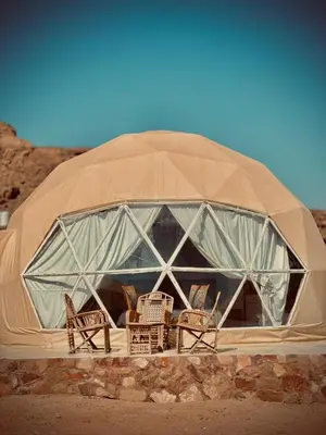 a dome tent with chairs and tables in it at ROYAL LANCASTER lUXURY CAMP in Wadi Rum