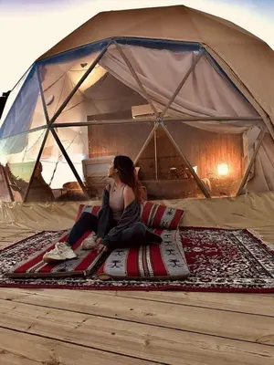 a woman sitting on a blanket in a tent at Moon Red Bubbles Camp in Wadi Rum