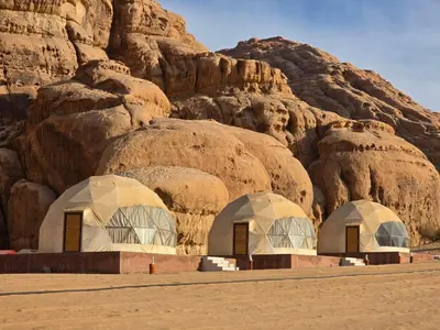 two domes in the desert next to a mountain at Amira Luxury Camp in Wadi Rum