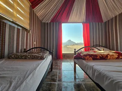 a room with two beds and a window with a view at Amira Luxury Camp in Wadi Rum