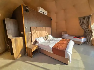 a bedroom with a large bed and a small at Amira Luxury Camp in Wadi Rum