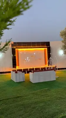 a building with two benches in the grass at مزرعة الخربه in Khirbat Abū al Khass