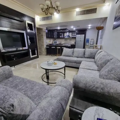 a large living room with couches and a tv at Deir Ghbar Suite in Amman