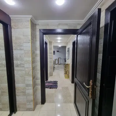 a hallway with a door and a hallway with tiles at Deir Ghbar Suite in Amman