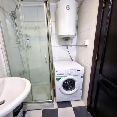 a bathroom with a washing machine and a sink at Deir Ghbar Suite in Amman