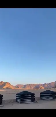 three tents in the desert with mountains in the background at وادي رم in Wadi Rum