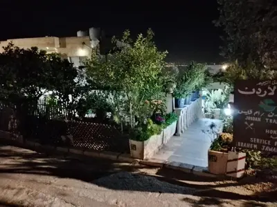 a house at night with a sign and plants at اربد ام قيس طريق درب الاردن in Um Qeis