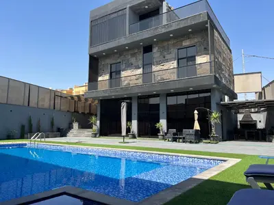 a house with a swimming pool in front of a building at Villa Ohaio in Amman