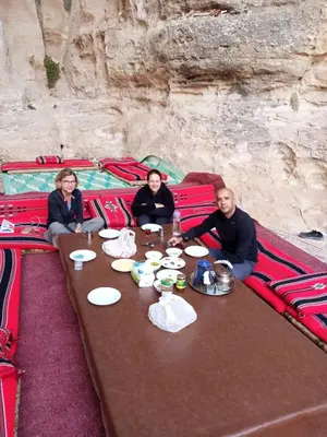 a group of people sitting at a table with food at Halfway motel in An Namatah