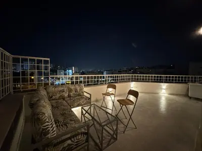a balcony with chairs and couches on a roof at night at Roof 99 in Amman