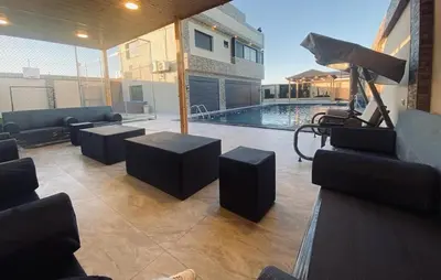 a living room with couches and a swimming pool at Sky Villa in Amman