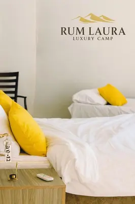 a white bed with yellow pillows on top of it at Rum Laura luxury camp in Wadi Rum