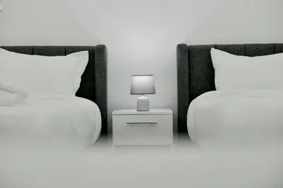 a bedroom with two beds and a lamp on a night stand at Rose In Apartment in Wadi Musa