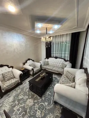 a living room with white furniture and a chandelier at Toum's Apartments 2 in Amman