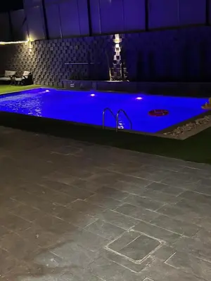 a blue swimming pool in a room with a table at Ohio villa in Sowayma
