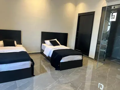 a bedroom with two beds and a glass shower at Ohio villa in Sowayma
