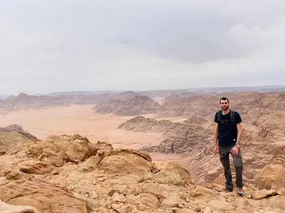 a man standing on a mountain in the desert at Desert Key Camp in Wadi Rum