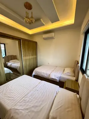 a bedroom with two beds and a chandelier at 2bd apartment sport city in Amman