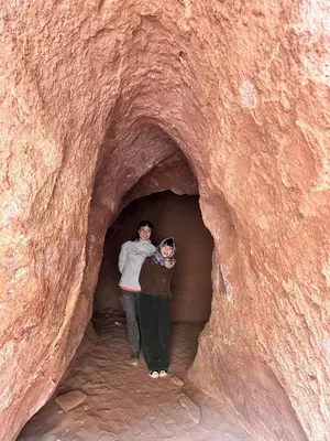 two people standing in a tunnel in a rock at Sleeping amidst the natural beauty of Wadi Rum, and living like a Bedouin in Aqaba
