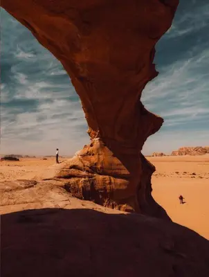 a man standing in a desert with a rock formation at Sleeping amidst the natural beauty of Wadi Rum, and living like a Bedouin in Aqaba