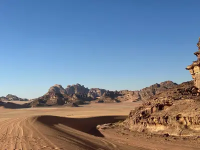 a dirt road in the desert with a mountain at Sleeping amidst the natural beauty of Wadi Rum, and living like a Bedouin in Aqaba