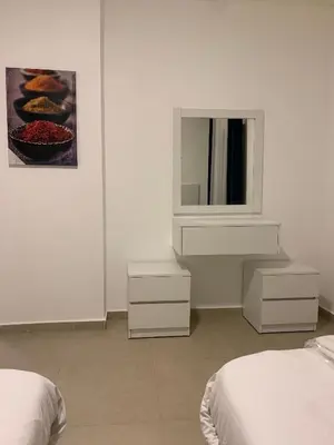 a white room with two beds and a television at Luxurious 3 Bedroom Apartment in Heart of Amman in Amman