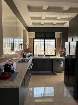 a large kitchen with black and white appliances at Sports city 2bd room in Amman