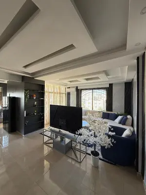 a living room with a blue couch and a tv at Sports city 2bd room in Amman