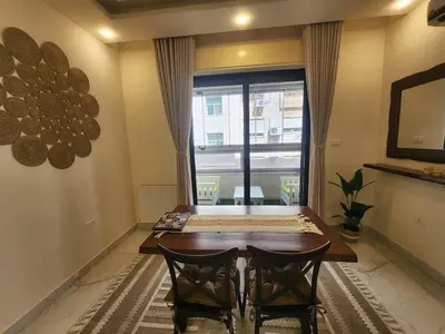 a dining room with a table and two chairs and a window at Cozy Appartment In Shmessani in Amman