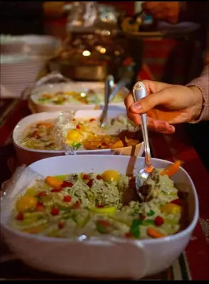 a person eating a bowl of food on a table at Wadi Rum Bubble Dream in Wadi Rum