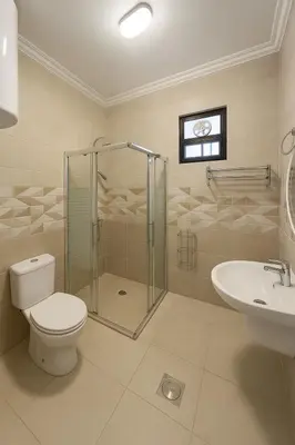 a bathroom with a shower and a toilet and a sink at Pine Country Farm Stay in Umm al Manābī‘