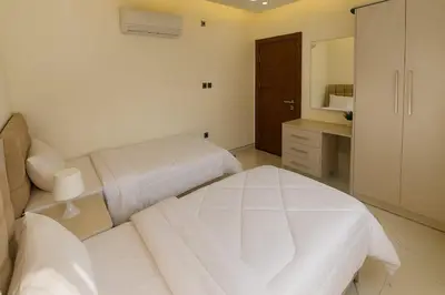 a white bedroom with two beds and a mirror at Central Amman Twin Towers Apartment 2 in Amman