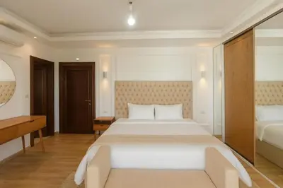 a bedroom with a large white bed and a desk at Prime City Luxury Apartment in Amman