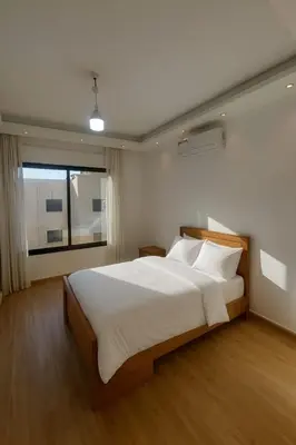 a bedroom with a large white bed with a window at Prime City Luxury Apartment in Amman