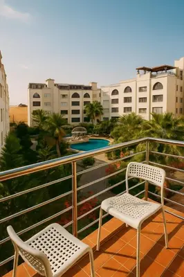 a balcony with two chairs and a swimming pool at Elite Apartment Compound in Amman