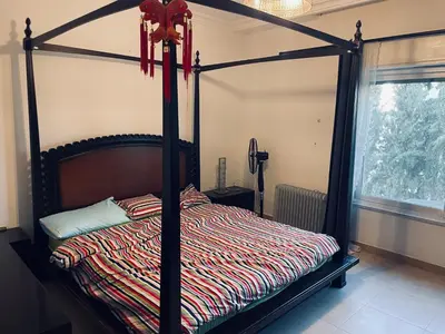 a black canopy bed with a striped comforter in a bedroom at Furnished Villa in Andalusian Compound for Rent in Madaba