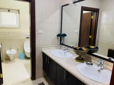 a bathroom with two sinks and a toilet and a mirror at Furnished Villa in Andalusian Compound for Rent in Madaba