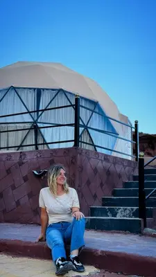 a woman sitting on the steps in front of a building at BUBBLE lUXURY RUM JNOPE CAMP in Wadi Rum