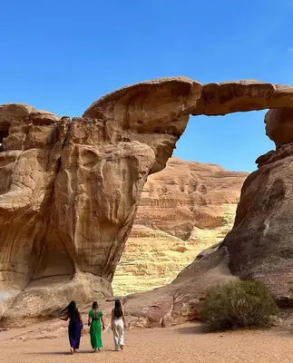 three women walking through an arch in the desert at BUBBLE lUXURY RUM JNOPE CAMP in Wadi Rum