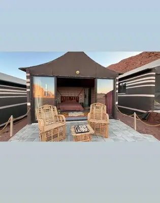 a tent with chairs and a bed on a patio at Wadi Rum Wanderer cmap in Wadi Rum