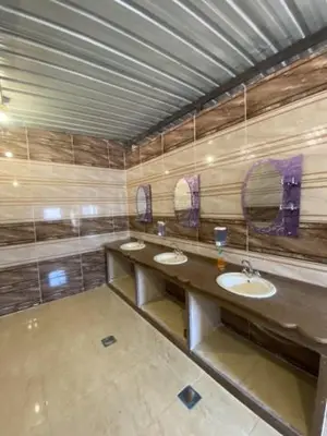 a bathroom with three sinks and two mirrors at Wadi Rum Nights Tents in Wadi Rum